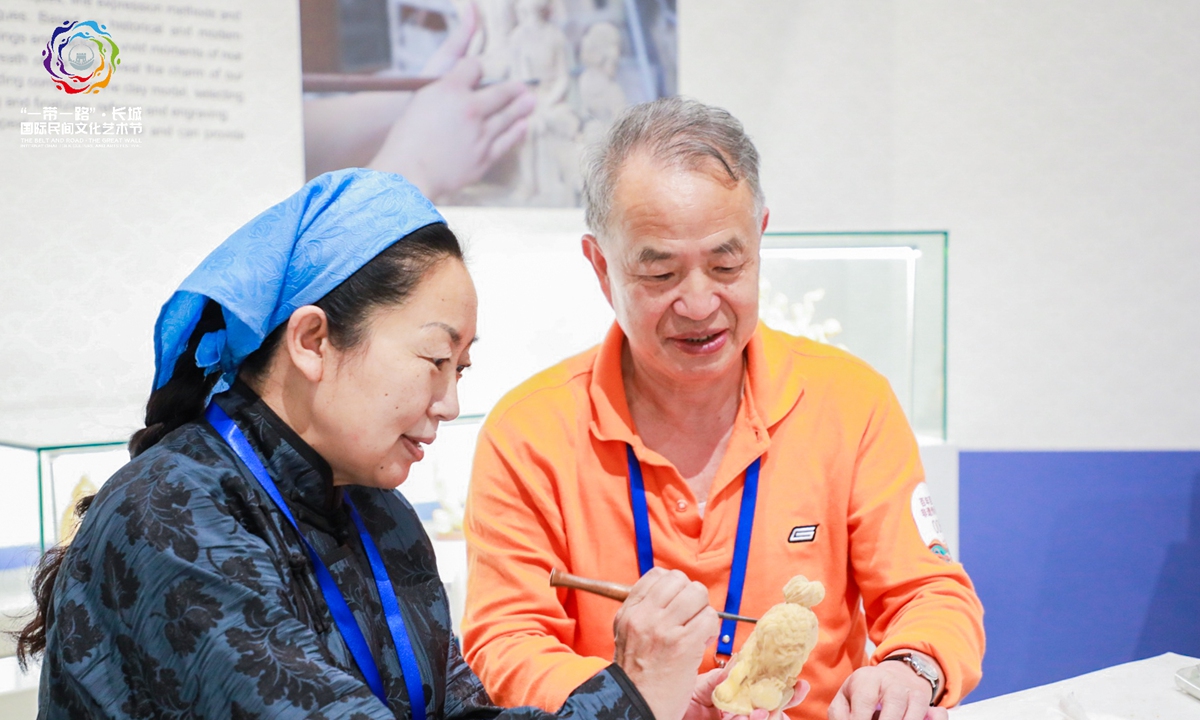 A silk market at the Belt and Road and the Great Wall International Folk Culture and Arts Festival 2021 Photos: Courtesy of Jiao Guoyuan ?A Chinese fan?A handicraftsman shows her woodcarving skills to a visitor at the Great Wall International Folk Culture and Arts Festival 2021 in Langfang, North China's Hebei Province, on Thursday. 