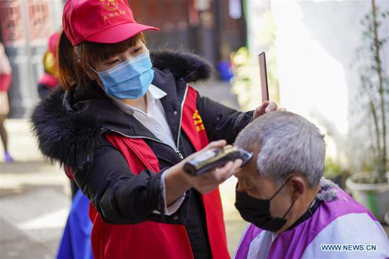 A volunteer barber (L) cuts a man's hair at a community in southwest China's Chongqing Municipality, Feb. 16, 2020. Since the outbreak of the novel coronavirus, most barbershops have been closed. A community in Beibei District of Chongqing organized a team of volunteer barbers to provide free haircuts for its residents. (Xinhua/Liu Chan)