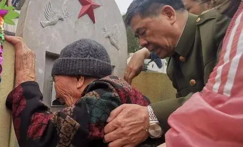 蔡朝东背着老人,志愿者一行相伴,随家属来到烈士墓前.