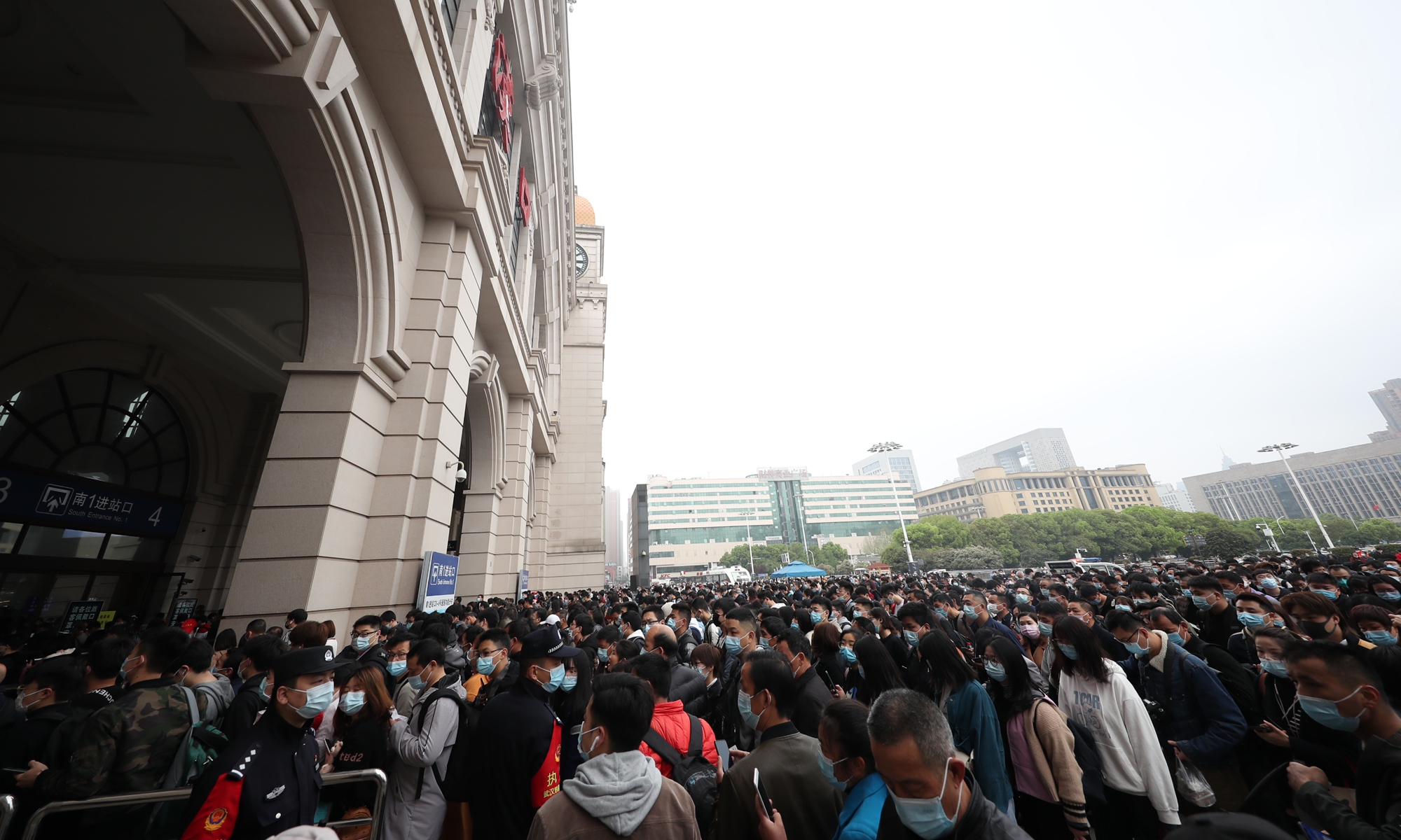 Two police officers look on while travelers enter the Hankou Railway Station in Wuhan on Saturday, the first day of the Qingming Festival holidays. Photo: VCG